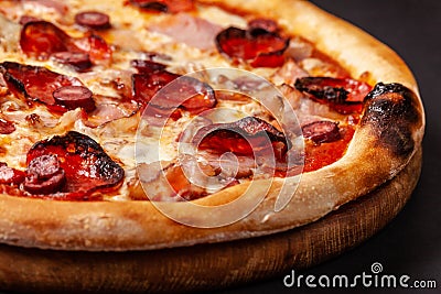 The concept of Italian cuisine. Real Italian pizza on a thin cake with large sides on a black background. Close up. Background Stock Photo