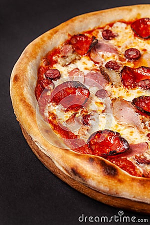 The concept of Italian cuisine. Real Italian pizza on a thin cake with large sides on a black background. Close up. Background Stock Photo