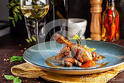 Concept of Italian cuisine. Stewed chicken in strong wine with vegetables. Serving dishes in a restaurant in a blue plate Stock Photo