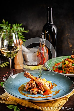 Concept of Italian cuisine. Stewed chicken in strong wine with vegetables. Serving dishes in a restaurant in a blue plate Stock Photo