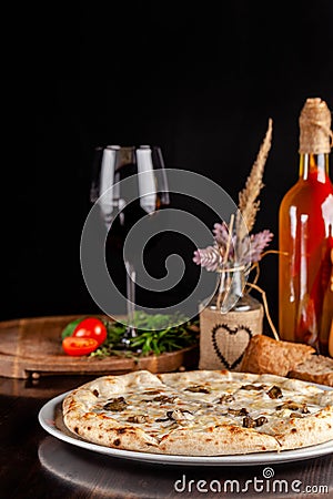 The concept of Italian cuisine. Thin cheese pizza with mushrooms, with large sides of Semola flour. A string of red wine Stock Photo