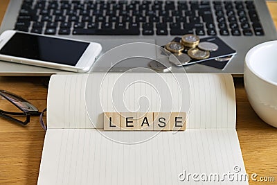 Concept keyword lease in generic wooden tile letters in personal home desk setting with laptop, notebook and accessories Stock Photo