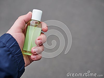 Concept of living in a new reality of coronavirus epidemic hysteria man`s hand holding sanitizer gel bottle outdoors on city Stock Photo