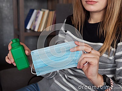 Concept of living in a new reality of coronavirus epidemic hysteria woman`s hand holding sanitizer bottle and medical mask street Stock Photo