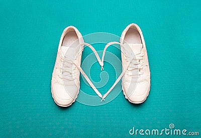 The concept of love for fitness. white sneakers with a heart, on a bright blue background. selective focus Stock Photo