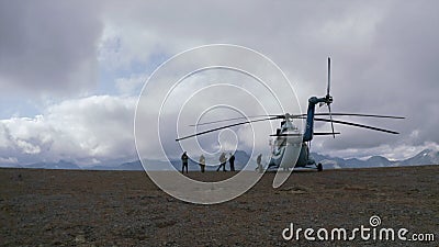 Concept of luxury and expensive tourism: group of people near helicopter on a mountain top. Clip. Hikers exploring Editorial Stock Photo