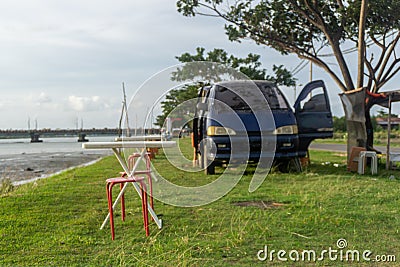 chair and table infront of campervan. Picnic concept. campervan parked under the tree and beside the river. concept of mobile Editorial Stock Photo