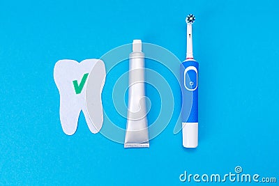 The concept of modern dental care products. Electric toothbrush, toothpaste, a tooth cut out of felt with a green ok icon. Blue Stock Photo