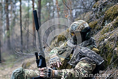 Concept of modern warfare - a mercenary soldier is resting after a clash in the forest. Stock Photo