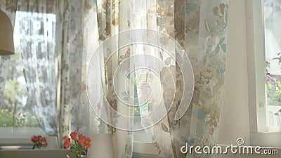 The concept of morning. beautiful curtains with a floral print are waving in the wind from a half-open window. sun glare Stock Photo