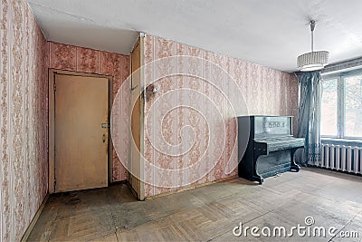 Old ugly abandoned unfurnished room with a dusty black piano Stock Photo