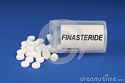 On a blue surface are pills and a dusty jar with the inscription - Finasteride Stock Photo