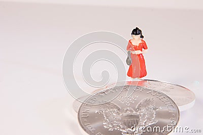 A female figure standing beside United States silver eagle one ounce coins with the concept of seeking wealth Stock Photo