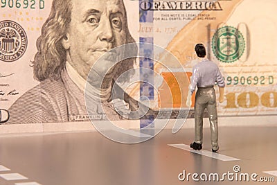 A male figure walking toward United States paper currency with the concepts of seeking wealth Stock Photo