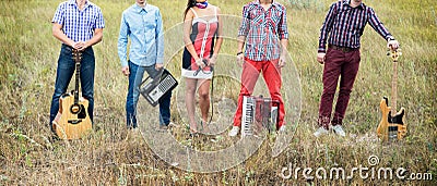 Concept photo of music band with guitars, microphone and accordion standing outdoors Stock Photo