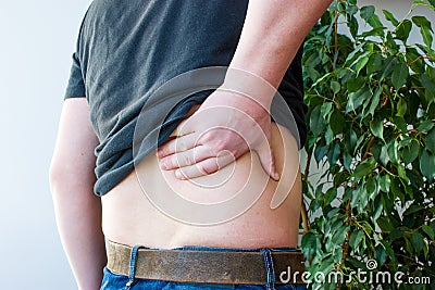 Concept photo of pain in kidney. Person put his hand in middle on side of back surface in anatomical projection of kidneys. Pain s Stock Photo