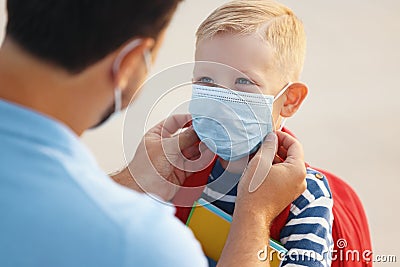 Concept of preventing a coronavirus covid-19 and viral infections. Father puts on medical mask for little son before school Stock Photo