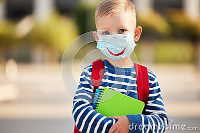 Concept of preventing a coronavirus covid-19 and viral infections. Little schoolboy in a medical mask with a painted smile before Stock Photo