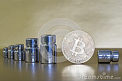 The concept of reducing the cost and rate of cryptocurrency. Bitcoin with weights, showing the growth and decline Stock Photo