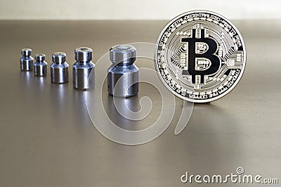 The concept of reducing the cost and rate of cryptocurrency. Bitcoin with weights showing weight, growth and decline. Stock Photo