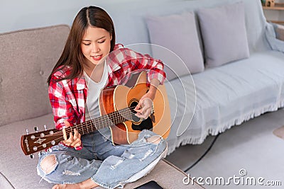 Concept of relaxation with music, Young woman sings and plays acoustic guitar after learning music Stock Photo