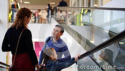 Concept of relaxing family. Father, mother and daughter on escalator Stock Photo