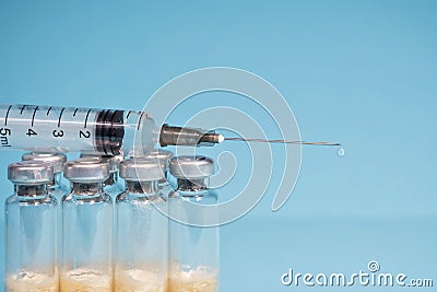 The concept of routine vaccination of the population.A medical syringe with a dose of medicine and a dripping drop lies Stock Photo