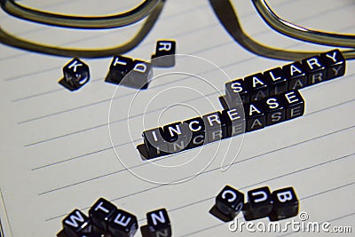 concept of Salary Increase on wooden cubes with glass eye, books in Vintage background Stock Photo