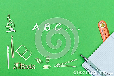 Letters abc, school supplies wooden miniatures, notebook with ruler, pen on green backboard Stock Photo