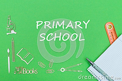 Text primary school, school supplies wooden miniatures, notebook with ruler, pen on green backboard Stock Photo