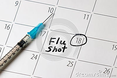 Flu shot reminder on calendar with needle syringe Stock Photo