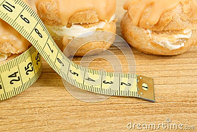 Concept of slimming, closeup of caramel cakes with measuring tape Stock Photo