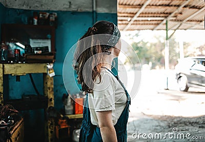 The concept of small business, feminism and women`s equality. A young woman in work clothes looks at the street from an auto Stock Photo