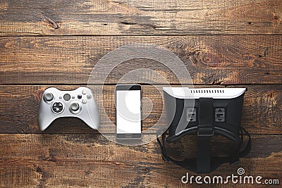 The concept of smart gaming. top view of gamepad, smartphone, VR glasses on wooden background with copy space Stock Photo