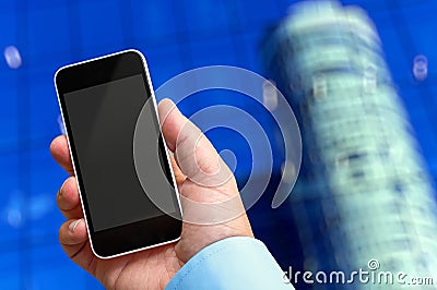 Smartphone in hand with a blank area to insert a custom image. Modern building on background Stock Photo