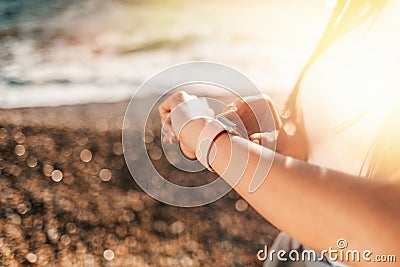 The concept of sport. Female hands with a wristwatch close-up. In the background, the coast and the sea. Copy space Stock Photo