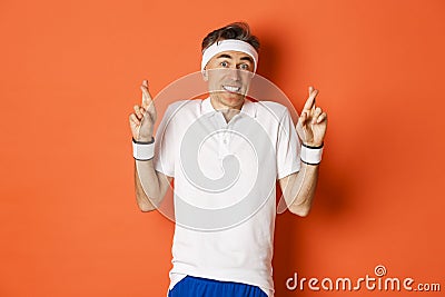 Concept of sport, fitness and lifestyle. Portrait of hopeful middle-aged male athlete, crossing fingers for good luck Stock Photo