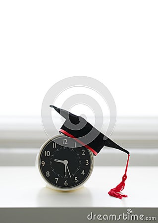 A mortarboard on an alarm clock in white background Stock Photo