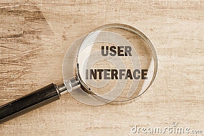 The concept of technology and development. Phrase, word, text USER INTERFACE through a magnifying glass, top view Stock Photo