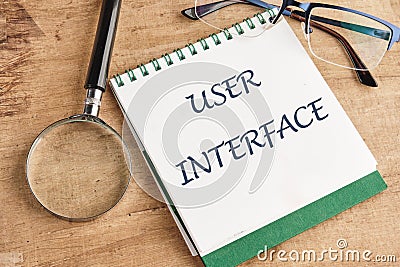 The concept of technology and development. Phrase, word, text USER INTERFACE in a notebook on an old background, in a Stock Photo
