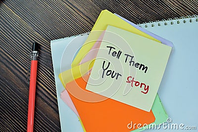 Concept of Tell Them Your Story write on sticky notes isolated on Wooden Table Stock Photo