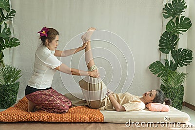 Concept thai Massage. Asian young woman getting thai herbal massage in spa salon.Thai girl stretching her legs with Stock Photo