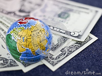 Concept of travel, small globe on background of dollars Stock Photo