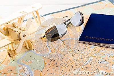 Concept of travelling, shopping, vacation, rest and relax. Cllose-up of map of roads, passport, sunglasses and wooden plane on li Stock Photo