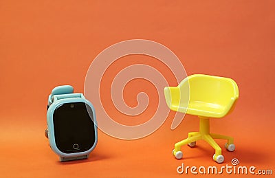 Concept of vacant chair. Yellow stool with blue kid smart watch on orange clean background. Photo in minimal style Stock Photo