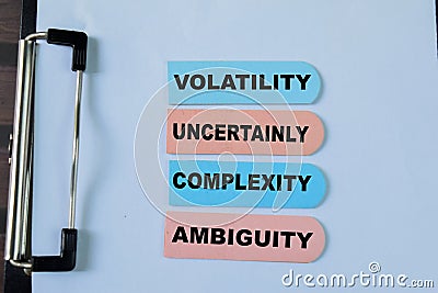 Concept of Volatility, Uncertainly, Complexity, Ambiguity write on sticky notes isolated on Wooden Table Stock Photo