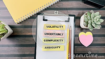 Concept of VUCA - Volatility Uncertainly Complexity Ambiguity write on sticky notes isolated on Wooden Table Stock Photo