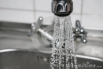 Concept water saving at home, reducing use. Water tap with flowing water with spray. Selective focus Stock Photo