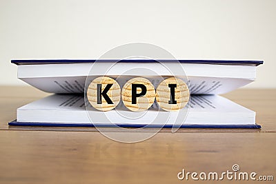 Concept word `KPI - key perfomance indicator` on wooden circles between pages of a book on a beautiful wooden table. White Stock Photo