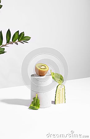Conceptual creative still life with green fruits and cucumber on concrete podiums on a white background Stock Photo